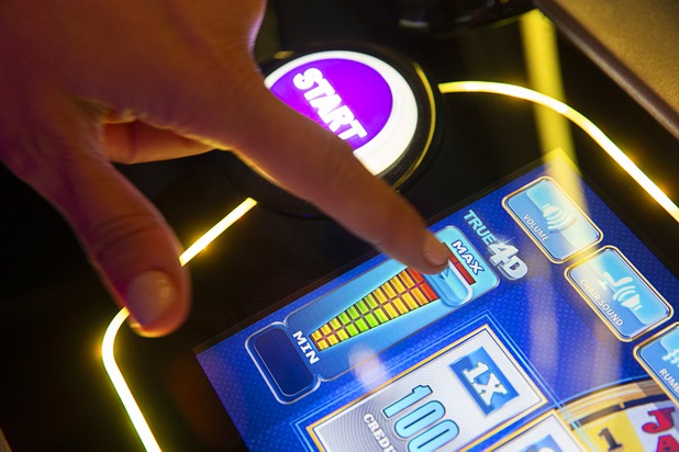 A woman adjusts the intensity on a IGTs Wheel of Fortune 4D Collectors Edition slot machine during the Global Gaming Expo (G2E) at the Sands Expo Center Tuesday, Oct. 5, 2021. The machines have 4D technology built into the seats.