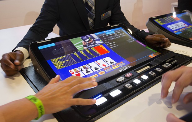 Attendees look over the IGT Peak BarTop machine during the Global Gaming Expo (G2E) at the Sands Expo Center Tuesday, Oct. 5, 2021. The machine can play the traditional slot machine and video poker games but also incorporates sports betting and live sports viewing.