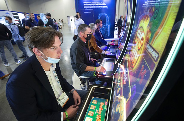 Levi Elliott, left, a technician with Longhorn Amusement, tries out a new slot machine game during the Global Gaming Expo (G2E) at the Sands Expo Center Tuesday, Oct. 5, 2021.