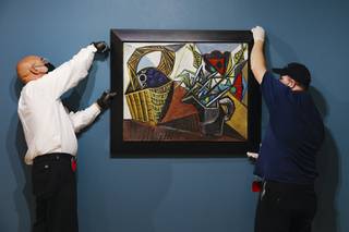 From left, Jose Reynoso and Terence McAllister hang a still life painting by Pablo Picasso at the Bellagio Gallery of Fine Art Tuesday, Oct. 19, 2021.