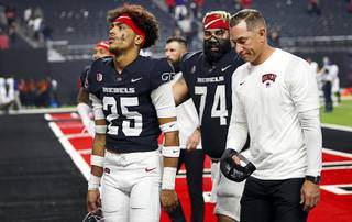 UNLV Rebels head coach Marcus Arroyo leaves the field with defensive back Cameron Oliver (25) and offensive lineman Julio Garcia (74) after a 27-20 loss to the San Jose State Spartans at Allegiant Stadium in Las Vegas Thursday, Oct. 21, 2021.