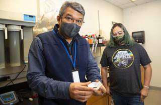 Eric Bandala, an environmental engineer, displays a patented biochar in a lab at the Desert Research Institute (DRI) Tuesday, Oct. 19, 2021. Adam Clurman, a Nevada State College student, is at right. The patented biochar developed art DRI, is especially good at removing nitrates from water.