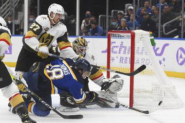 St. Louis Blues’ Robert Thomas (18) and Vegas Golden Knights’ Shea Theodore (27) vie for the puck after a missed shot on goal during the second period of an NHL hockey game Monday, Nov. 22, 2021 in St. Louis. 