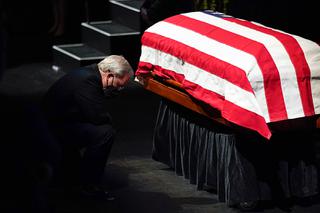 A man kneels before the flag-draped casket of former Senate Majority Leader Harry Reid after a memorial service for Reid at the Smith Center in Las Vegas, Saturday, Jan. 8, 2022.