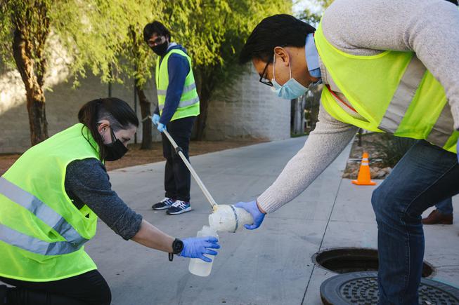 From left, lab technician Liz Dahlmann, undergraduate research assistant Nabih Ghani and Edwin Oh, Ph.D., Associate Professor at the Kirk Kerkorian School of Medicine demonstrate their process for collecting a wastewater sample at UNLV Tuesday, Jan. 11, 2022.