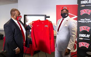 UNLV President Keith Whitfield, left, presents Erick Harper with a customized jersey and cap after Harper was officially introduced as UNLVs new athletic director during a news conference at the Thomas & Mack Center Wednesday, Jan. 12, 2022.