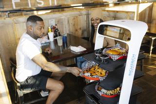 A Richtech Robotics Matradee robot delivers food to Maurice Smith and Najee Smith at Catchers Fish House Friday, Feb. 11, 2022. Employees have named the robot Caribbean Mike.