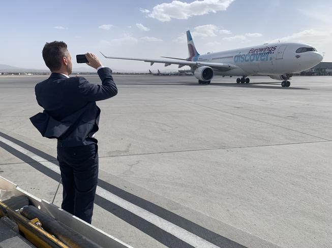 Marco Gotz, an executive with German air carrier Lufthansa Group, takes a picture with his cellphone as a Eurowings Discover Airbus A330-300 jet arrives at Harry Reid International Airport in Las Vegas late afternoon on March 28, 2022