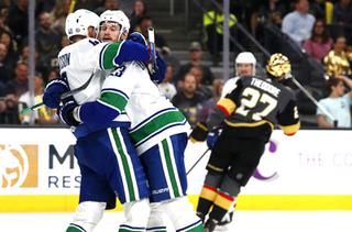 Vancouver Canucks center Elias Pettersson (40) celebrates with defenseman Oliver Ekman-Larsson (23) after scoring during the second period of an NHL hockey game against the Vegas Golden Knights at T-Mobile Arena Wednesday, April 6, 2022. Vegas Golden Knights defenseman Shea Theodore (27) skates away at right.