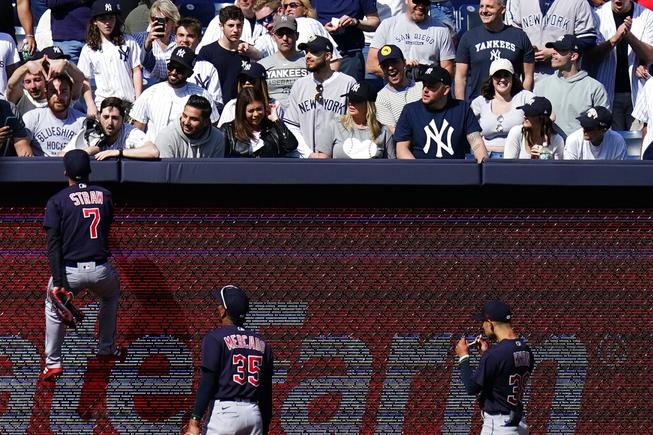 Cleveland Guardians' Myles Straw (7) climbs the left field wall to talk with a fan during the ninth inning of a baseball game against the New York Yankees Saturday, April 23, 2022, in New York. The Yankees won 5-4. (AP Photo/Frank Franklin II)


