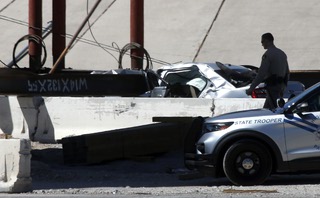 A Metro Police officer walks by a car that was crushed by a steel beam at the I-215 and U.S. 95 interchange under construction in the northwest valley Friday, June 10, 2022. The driver was the car was killed in the accident, according to Nevada State Police.
