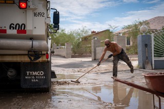 Robert Rodriguez, the brother of the homeowner Carlos Rodriguez, help sweep water back on to the streets and away from their property on N.Clayton St in East Las Vegas. Monday, August 15th, 2022.