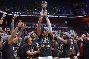 Las Vegas Aces' A'ja Wilson holds up the championship trophy as she celebrates with her team their win in the WNBA basketball finals against the Connecticut Sun, Sunday, Sept. 18, 2022, in Uncasville, Conn. Kelsey Plum and Chelsea, to Wilson's left and right respectively, will join Wilson to go for another trophy. The trio will head to Australia to represent the US in the women's basketball World Cup, which starts Thursday.