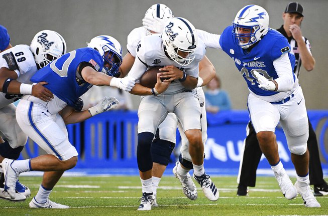 Air Force linebacker Alec Mock, second from left, and defensive end Jayden Thiergood, right, bring down Nevada quarterback Nate Cox, center, after a short gain during the first half of an NCAA college football game Friday, Sept. 23, 2022, in Air Force Academy, Colo. (Christian Murdock/The Gazette via AP)

