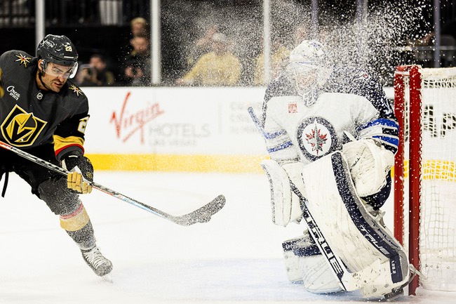 Vegas Golden Knights left wing William Carrier, left, takes a shot on goal against Winnipeg Jets goaltender Connor Hellebuyck during the second period in an NHL hockey game, Sunday, Oct. 30, 2022, in Las Vegas.