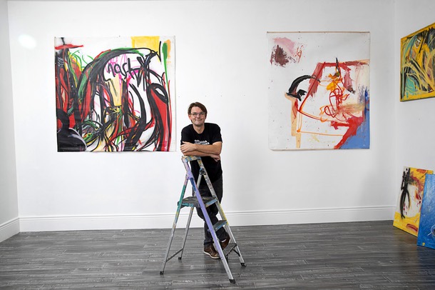 Artist Brian C. Gibson poses with artwork as he sets up for his show titled Boytoy Summer at Inside Style on Main Street Thursday, Nov. 3, 2022. Artwork shown is: Nashville, TN (White-on-White Crime), left, and Automatic Fool. The show runs through Nov. 30.