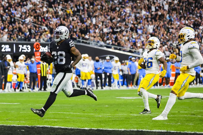 Las Vegas Raiders running back Josh Jacobs (28) runs the ball into the end zone as Los Angeles Chargers cornerback Asante Samuel Jr. (26) chases after him during the first half of an NFL football game at Allegiant Stadium Sunday, Dec. 4, 2022.
