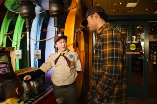 Webelos Scout Wyatt Norrbom, 9, center, of Boy Scouts Pack 96, tries to sell popcorn to a customer at Bass Pro Shops Sunday, Dec. 18, 2022.