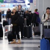 A traveler, right, checks on her cellphone as other travelers walk through Terminal 3 at O'Hare International Airport in Chicago, Thursday, Dec. 22, 2022. 

