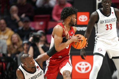 UNLV guard EJ Harkless, center, pulls the ball away from San Diego State guard Adam Seiko during the first half of an NCAA college basketball game Saturday, Feb. 11, 2023, in San Diego.