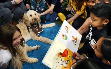 Hushed whispers echo throughout the gym at Legacy Traditional School in the southwest valley as a class of third-graders surround Lucy, a 4-year-old therapy dog. Each of the students gets the chance to read a page from “Pick Me!” by Greg Gormley ...