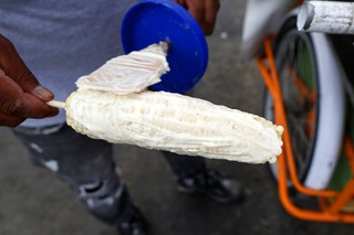 Street vendor Luis Sanchez spreads butter on an elote (corn on the cob with butter, mayonnaise and garnished with cheese) in a residential neighborhood in North Las Vegas Wednesday, June 14, 2023. Senate Bill 92, signed by Governor Lombardo last week, legitimizes street vendors across the state, providing them with the necessary permits to operate and grow their small businesses.