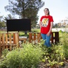 Madeline Kelly, a first grade teacher, poses by the vegetable and flower garden at Marion Earl Elementary School Friday, July 7, 2023.