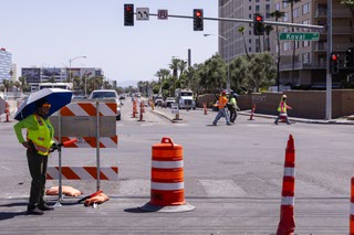 Construction workers cross Harmon Ave at Koval Ln Wednesday, Aug. 23, 2023.