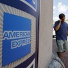 People walk past an American Express logo near the entrance to a bank in the Harvard Square neighborhood of Cambridge, Mass., Tuesday, July 19, 2011.