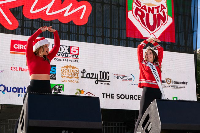 Brooke Kimball, from Lifetime Fitness & Miss Nevada, Taylor Blatchford, perform warm-up exercises to get the crowd ready for the Las Vegas Great Santa Run on Saturday, Dec. 2, 2023.