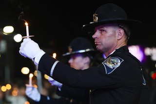 An officer holds a candle during a vigil for fallen Nevada State Police Sgt. Michael Abbate and Trooper Alberto Felix at Allegiant Stadium Thursday, Dec. 7, 2023. Abbate and Felix were assisting a motorist on the I-15 freeway when they were hit and killed by a drunk driver on Nov. 30, 2023.