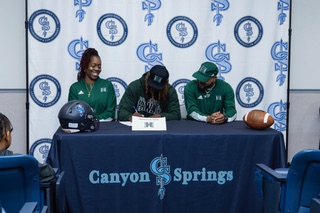 Canyon Springs High School football player Armando Lewis Jr., a wide receiver and defensive back, signs his letter of intent to play for University of Hawaii with his mother Tennille Davis and Canyon Springs football head coach Quincy Burts during signing day at the school Wednesday, Dec. 20, 2023. 
