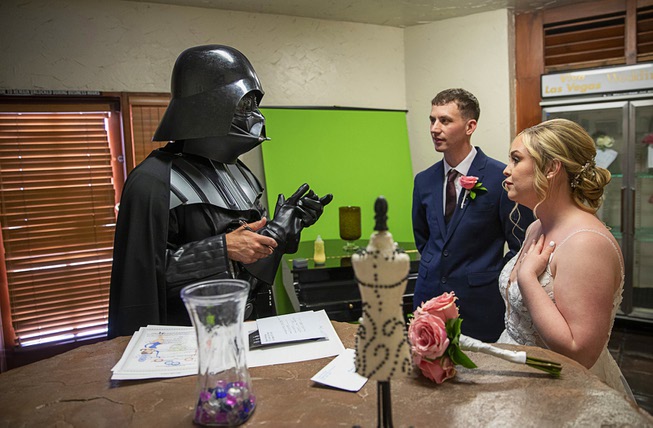 An officiate dressed as Darth Vader helps Edward and Megan Landau-Smith with their marriage certificate after they were married at the Viva Las Vegas Wedding Chapel Thursday, May 4, 2023. Chapels were busy all day with Star Wars-themed weddings as fans came to get married on May the Fourth (May The Force).