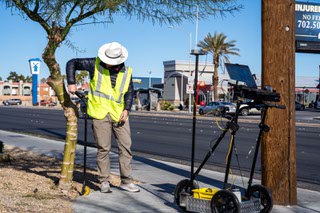 Beneficial Designs Inc. employee Issac Reid demonstrates the process methods of collecting sidewalk data for issues such as sinking, cracking, or obstructions, as well as collecting grade, cross slope and pavement type at the corner of S. Nellis Blvd and E. Vegas Valley Drive by using GPS coordinates to generate accurate collected data which is then included on to a map providing easy visual access to the assessment data collected for each client. Wednesday, January 10, 2023.