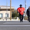 Clark County School District Police officer Keith Habig wears a heart costume as he crosses Russell Road with resident Zsanique Bryant  during a Valentines in a Crosswalk pedestrian safety event at Russell and Topaz Street Tuesday, Feb. 13, 2024.