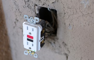 An outlet is shown hanging from the wall before a Nevada State Contractors Board news conference at a home Thursday, Feb. 29, 2024. Homeowner Barbara Ojito hired an unlicensed contractor to do work on her house but the man did shoddy work and never finished the job, she said.