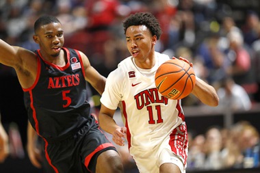 UNLV Rebels guard D.J. Thomas (11) drives past San Diego State Aztecs guard Lamont Butler (5) during the first half of an NCAA college basketball game in the quarterfinal round of the Mountain West Conference tournament, Thursday, March 14, 2024, in Las Vegas. 