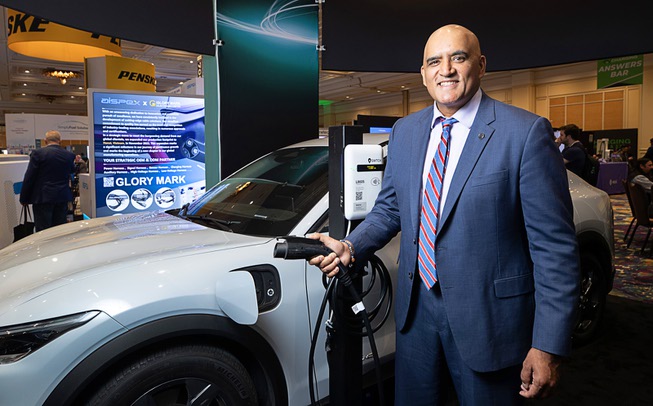 Federal Highway Administrator Shailen Bhatt poses by a Ford Mustang Mach-E electric vehicle in the SWTCH booth during the EV Charging Summit & Expo at the Mirage Thursday, March 21, 2024. SWTCH makes EV charger management software.