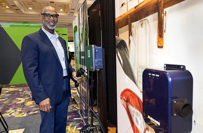David Ellis, vice president of engineering and product development at Dunamis Charge, poses by chargers during the EV Charging Summit & Expo at the Mirage Thursday, March 21, 2024.