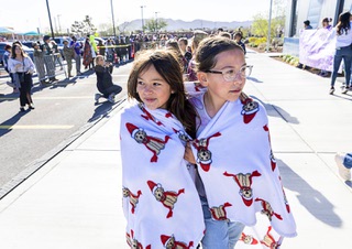 Fourth graders Sophia Kuhns, left, and Annie Kehoe share a blanket during a parade to mark the “Month of the Military Child” at Coral Academy of Science Las Vegas-Nellis Air Force Base Campus Friday, April 5, 2024.