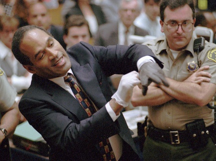 In this June 15, 1995, file photo, O.J. Simpson, left, grimaces as he tries on one of the leather gloves prosecutors say he wore the night his ex-wife Nicole Brown Simpson and Ron Goldman were murdered in a Los Angeles courtroom.