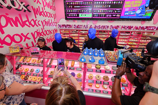 Members of Blue Man Group help out behind the counter during a promotional kick-off for Blue Man Group-inspired doughnuts at The Plaza in downtown Las Vegas Friday, April 12, 2024. The limited-edition doughnuts are called Blue Poo and Throwdown.