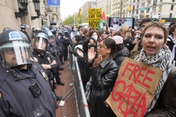 Police in Riot gear stand guard as demonstrators chant slogans outside the Columbia University campus, Thursday, April 18, 2024, in New York. U.S. colleges and universities are preparing for end-of-year commencement ceremonies with a unique challenge: providing safety for graduates while honoring the free speech rights of students involved in protests over the Israel-Hamas war. 

