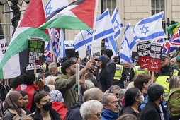 People take part in a pro-Palestine march as they walk past a counter protest with Israeli flags, at Waterloo Place in central London, Saturday, April 27, 2024.

