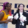 Indiana Fever players Aliyah Boston, left, and Caitlin Clark throw tee-shirts to fans during a time out during the first half between the Indiana Pacers and the Milwaukee Bucks in Game 2 in an NBA basketball first-round playoff series, Friday, April 26, 2024, in Indianapolis. 