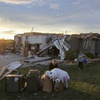 Two women help carry a friend's belongings out of their damaged home after a tornado passed through the area in Bennington, Neb., Friday, April 26, 2024. 