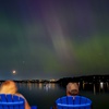 People view the northern lights, or aurora borealis, as they glow over Lake Washington, in Renton, Wash.