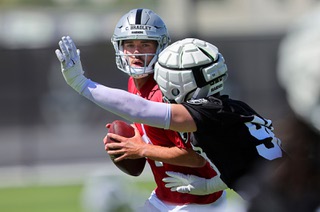 Las Vegas Raiders quarterback Carter Bradley (14) scrambles under pressure from defensive end Maxx Crosby (98) during organized team activities at the Las Vegas Raiders Headquarters/Intermountain Health Performance Center in Henderson Tuesday, May 21, 2024.