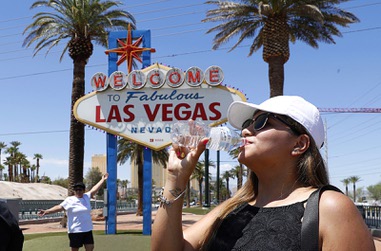 Sofia Ramirez of Mexico takes a drink of water after having her photo taken at the Welcome to Fabulous Las Vegas sign Thursday, June 6, 2024.