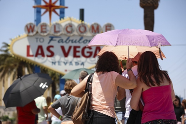 People use an umbrella to block the sun while waiting to take a picture at the “Welcome to Las Vegas” sign Monday, July 8, 2024, in Las&nbsp;Vegas. 